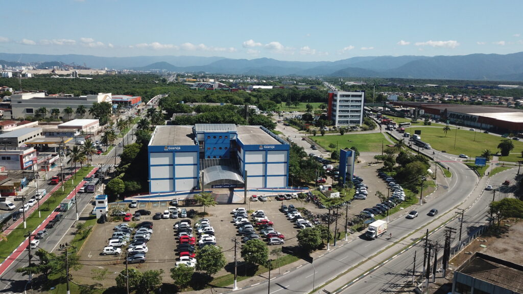 Vista aérea do Paço Municipal Raphael Vitiello, sede da Prefeitura de Guarujá, localizado em Vicente de Carvalho, com avenidas, prédios e áreas verdes ao redor.
